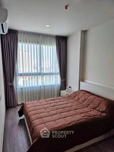 Cozy bedroom with large window and modern decor in urban apartment.