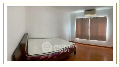 Spacious bedroom with wooden flooring and air conditioning, perfect for comfort and relaxation.