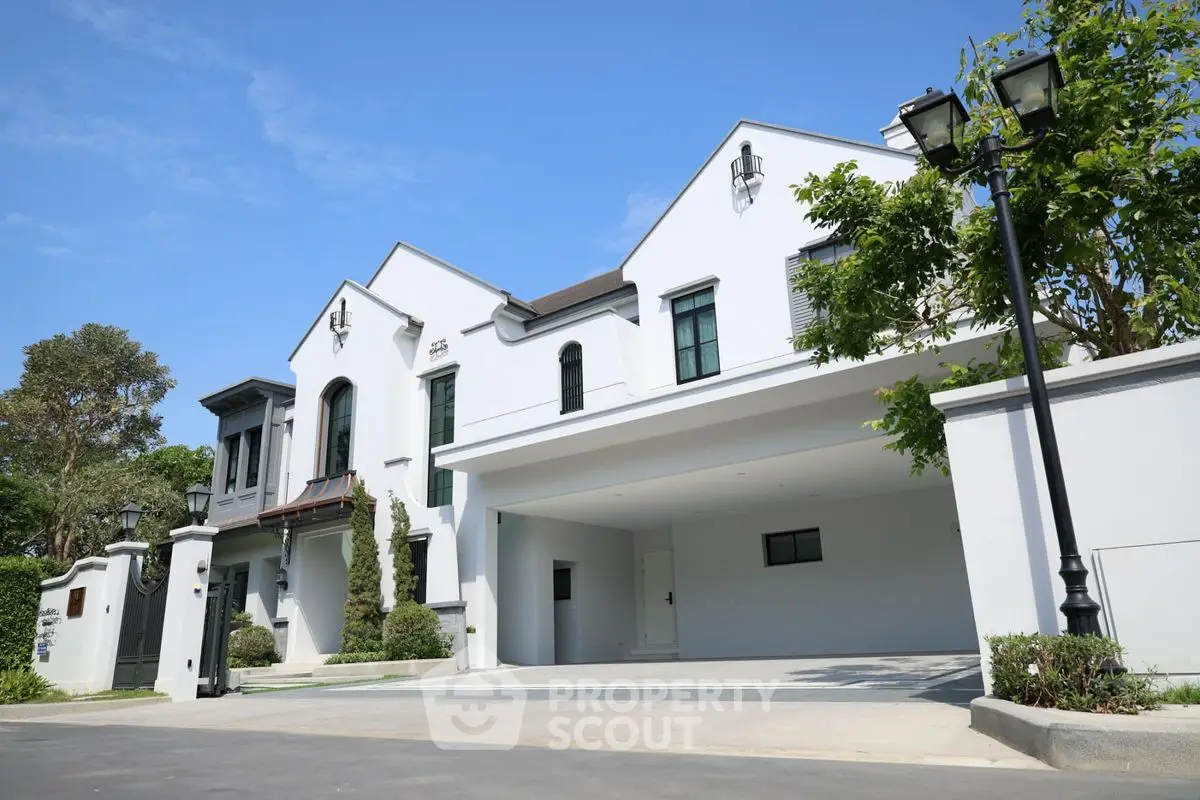 Luxurious modern white villa with spacious driveway and lush greenery