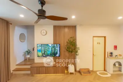 Modern living room with stylish decor and wooden accents, featuring a wall-mounted TV and ceiling fan.