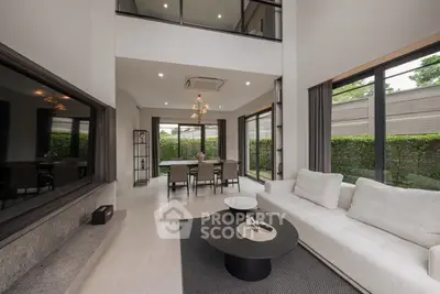 Luxurious modern living room with high ceilings and elegant decor, featuring large windows and stylish furniture.