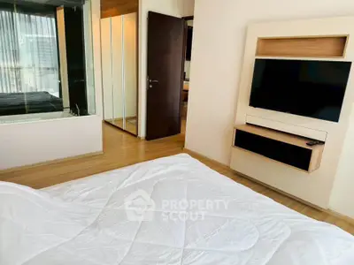 Modern bedroom with sleek wooden flooring and built-in TV unit, featuring a cozy bed and mirrored wardrobe.