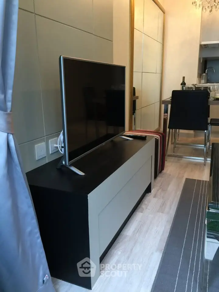 Modern living room with sleek TV setup and elegant dining area in a stylish apartment.