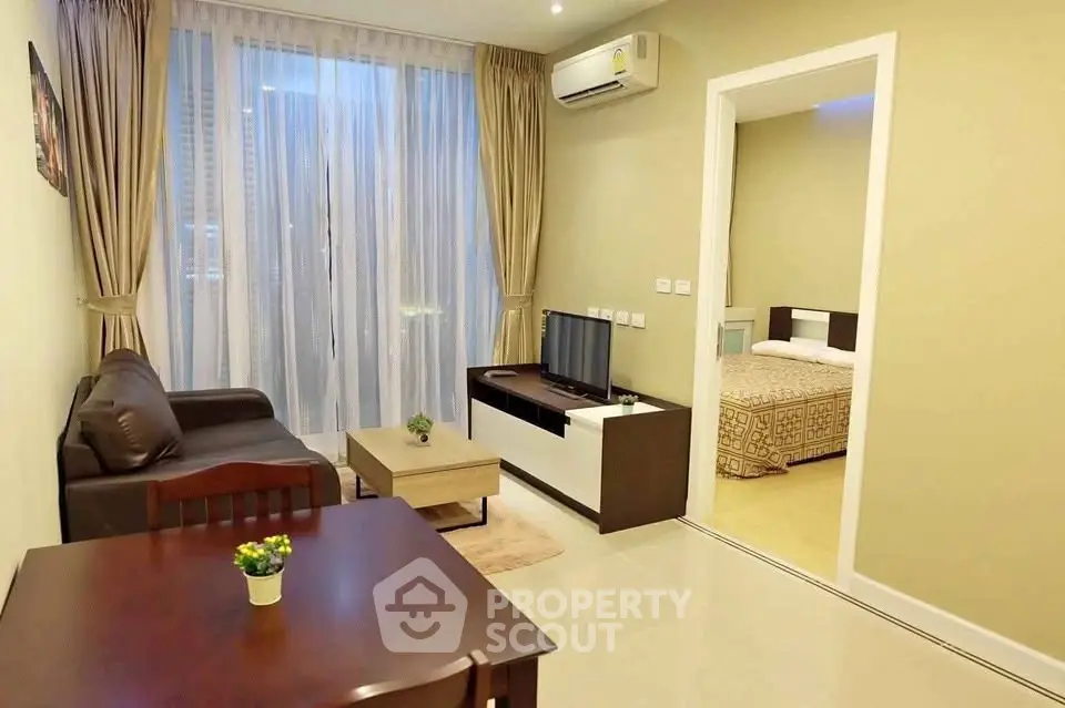 Modern living room with cozy sofa, TV, and dining area leading to a bedroom, featuring elegant curtains and lighting.