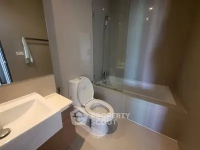 Modern bathroom with sleek fixtures and a glass-enclosed bathtub in a contemporary apartment.