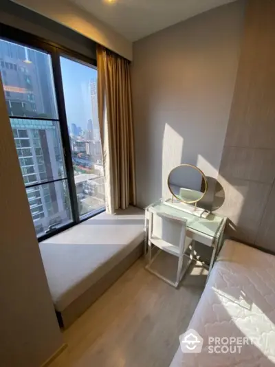 Cozy bedroom with city view, featuring a window seat and compact study desk.