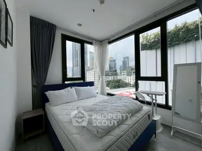 Modern bedroom with city view, featuring large windows and stylish decor.