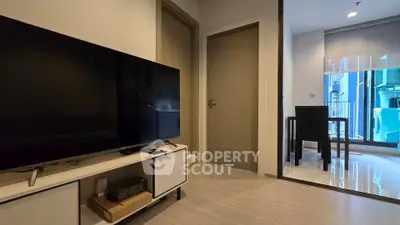Modern living room with sleek TV setup and dining area in a stylish apartment.