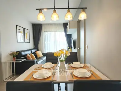 Modern living room with dining area, stylish lighting, and cozy decor in a contemporary apartment.