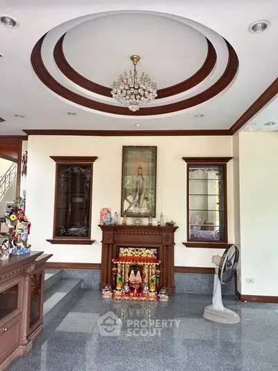Elegant living room with chandelier and decorative ceiling, featuring a stylish fireplace and polished flooring.