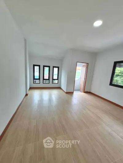 Spacious empty room with large windows and wooden flooring, perfect for customization.