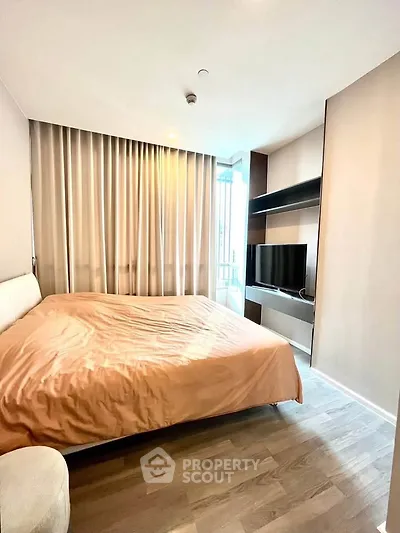 Modern bedroom with large window and sleek furnishings in a stylish apartment.