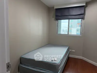 Cozy bedroom with stacked mattresses and a window view in a modern apartment.