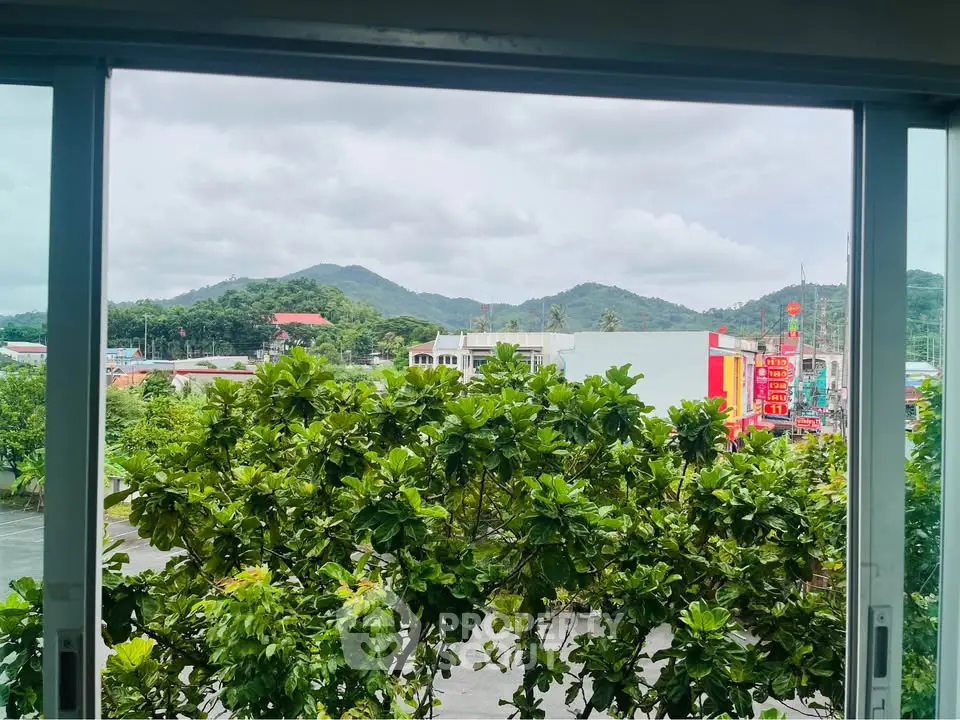 Scenic view from a window overlooking lush greenery and distant hills, perfect for nature lovers.