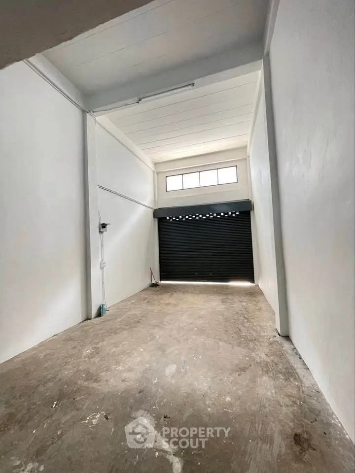 Spacious industrial storage unit with high ceiling and roller shutter door.