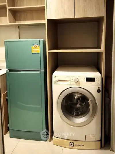 Modern kitchen with sleek appliances including a fridge and washing machine.