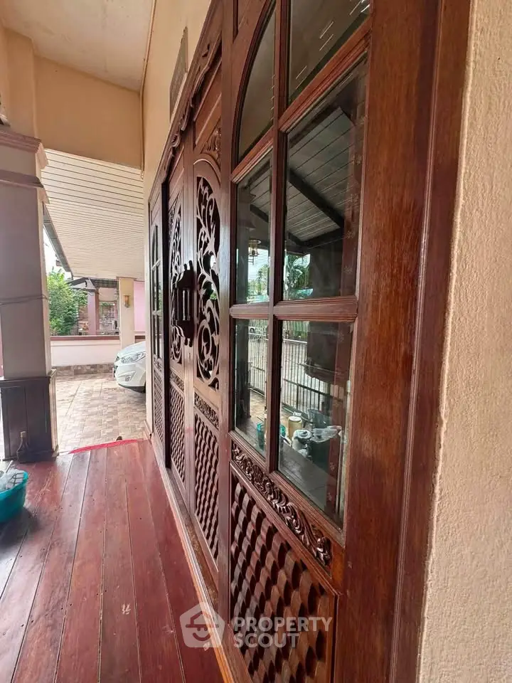 Elegant wooden entrance with intricate carvings and glass panels, showcasing a welcoming and stylish home exterior.