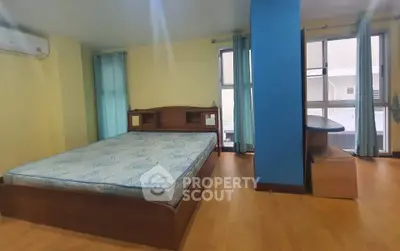 Spacious bedroom with large windows and wooden flooring