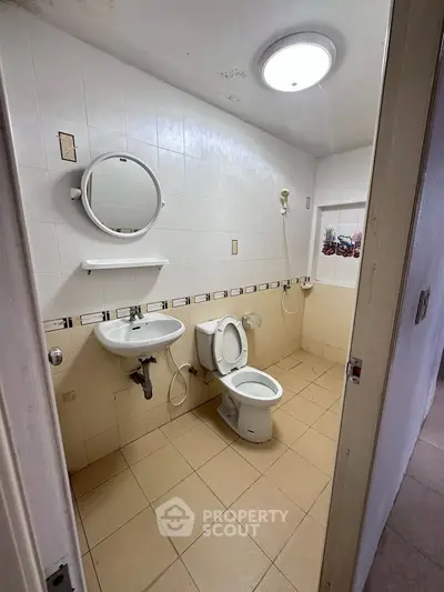 Compact bathroom with white tiles and basic fixtures, ideal for small spaces.