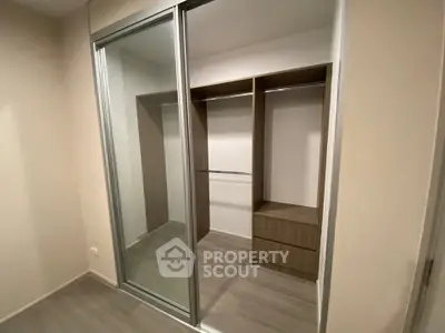 Spacious walk-in closet with sliding mirrored doors and modern wooden shelving.
