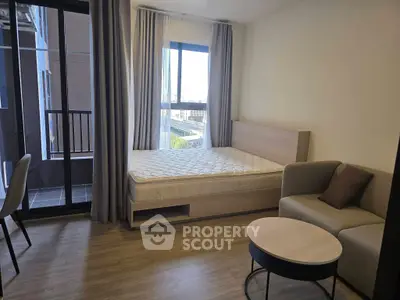 Modern studio apartment with balcony access and cozy furnishings.
