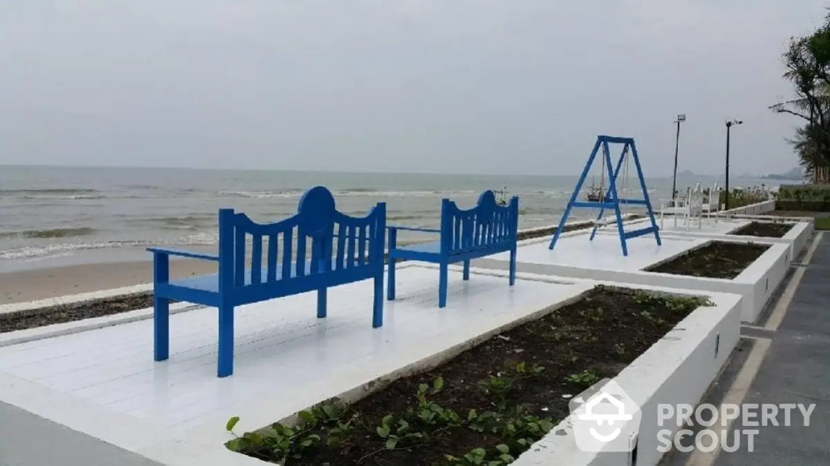 Stunning beachfront view with blue benches and swing, perfect for relaxation and leisure.