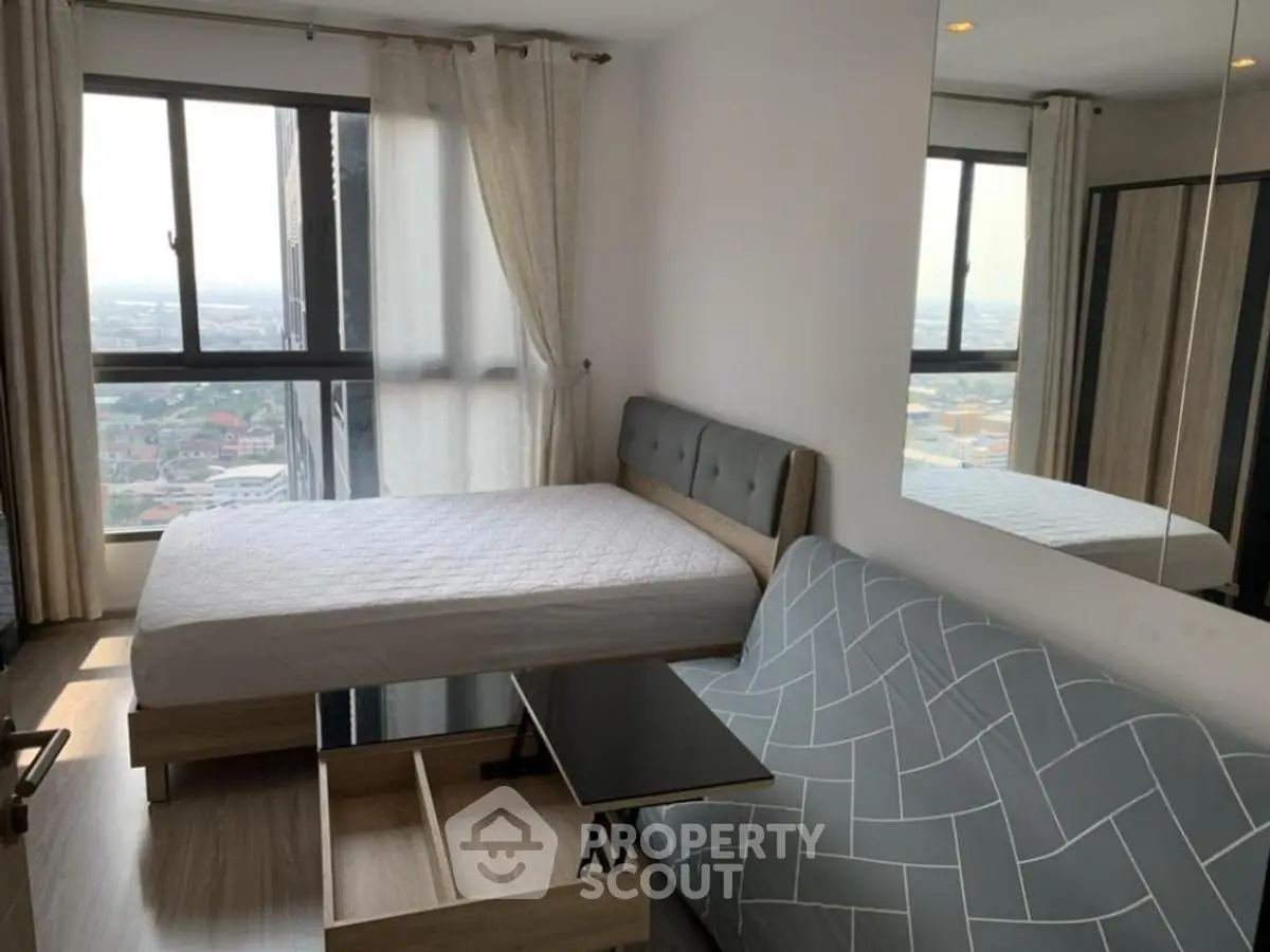 Modern bedroom with city view, featuring a stylish bed and cozy sofa.