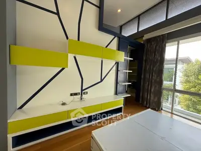 Modern living room with stylish geometric wall design and large window view.