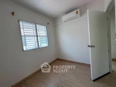 Bright empty room with wooden flooring and air conditioning, perfect for customization.