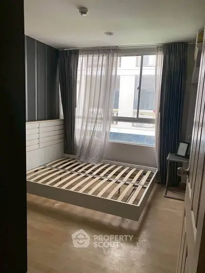 Spacious bedroom with large window and modern bed frame, perfect for natural light lovers.