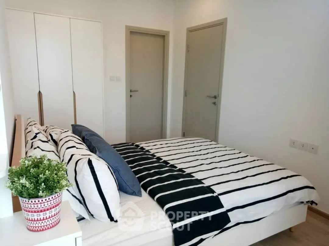 Modern bedroom with stylish decor and striped bedding in a cozy apartment.