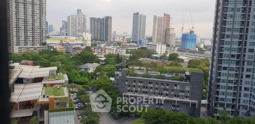 Stunning cityscape view from high-rise apartment overlooking lush greenery and modern buildings.