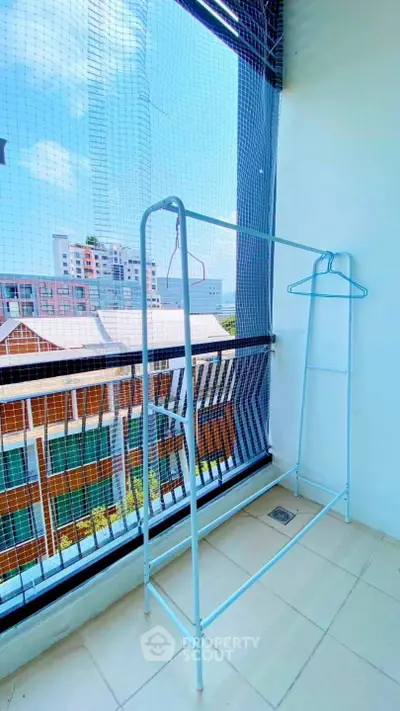 Spacious balcony with city view and clothing rack, perfect for urban living.