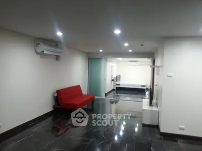 Spacious modern living room with sleek black flooring and red sofa