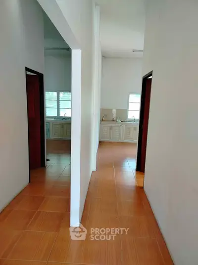 Spacious hallway leading to a bright kitchen with wooden flooring and ample natural light.