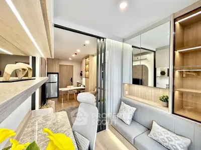 Modern open-layout living room with stylish decor and natural light, featuring a cozy seating area and sleek kitchen.