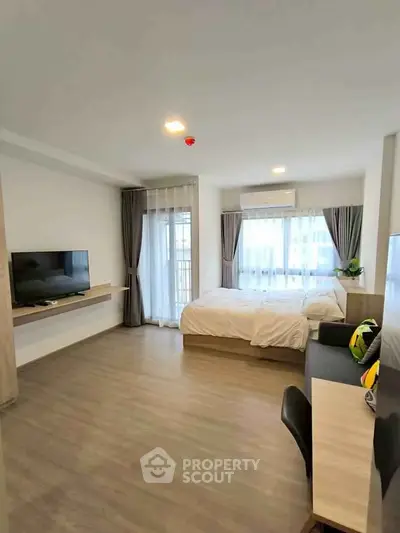 Spacious modern studio apartment with large windows and sleek wooden flooring.