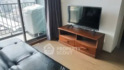 Modern living room with sleek TV stand and leather sofa, featuring a balcony view.