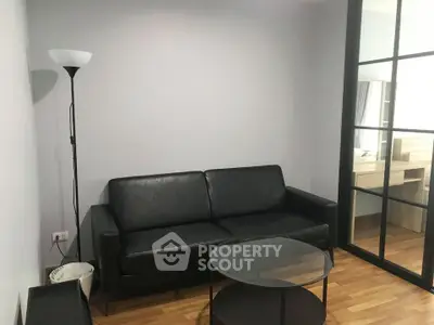 Modern living room with black leather sofa and glass coffee table on wooden floor