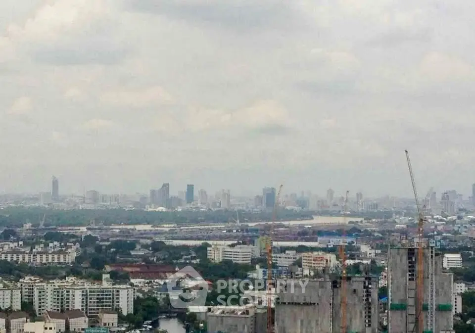 Panoramic cityscape view showcasing urban skyline and construction cranes under a cloudy sky.