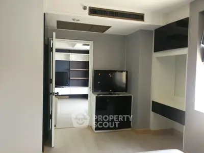 Modern bedroom with sleek black and white furniture, featuring a TV and ample storage space.