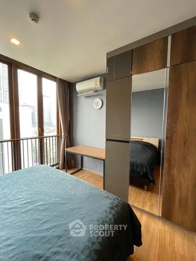 Modern bedroom with large windows and wooden flooring in a high-rise apartment.