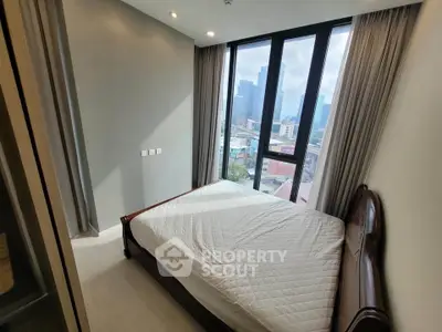 Modern bedroom with large windows offering stunning city views in a high-rise apartment.