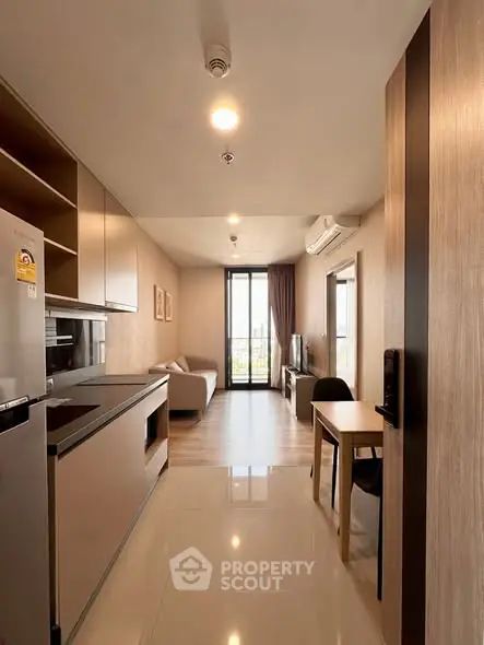 Modern open-plan living room with kitchen in a stylish apartment, featuring sleek furniture and a balcony view.