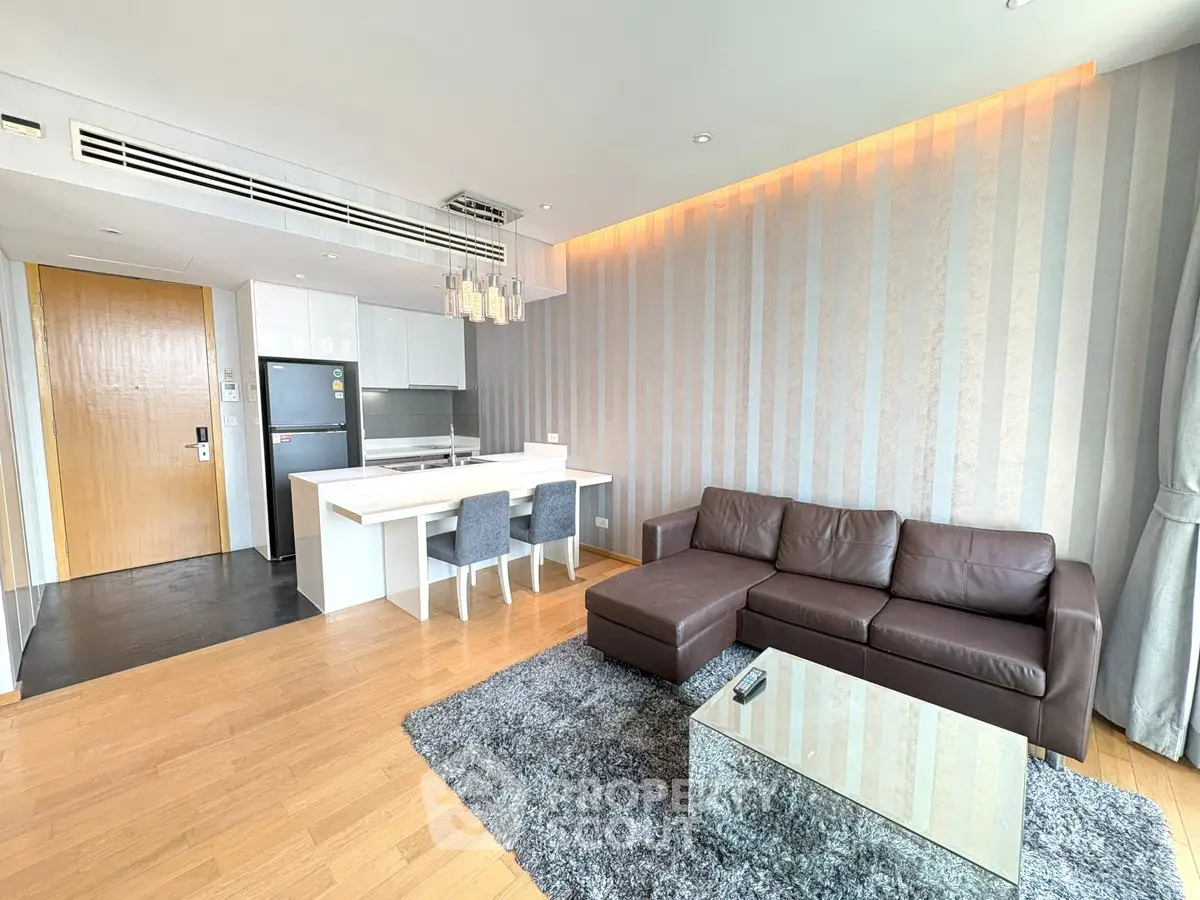 Modern living room with open kitchen, stylish decor, and cozy seating area.