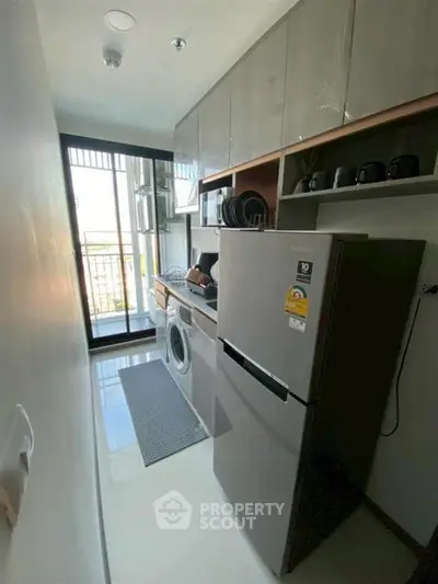 Modern kitchen with sleek appliances and balcony view in urban apartment