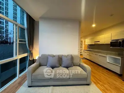 Modern open-layout living room with cozy sofa and sleek kitchen in urban apartment.
