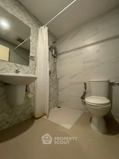 Modern bathroom with shower, toilet, and sink in a sleek design.