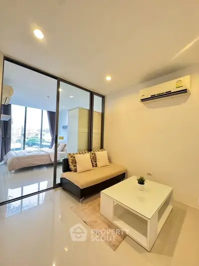 Modern living room with glass partition and air conditioning, featuring a cozy sofa and coffee table.