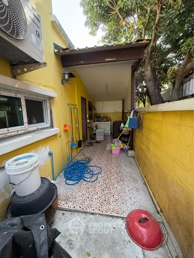 Charming outdoor utility area with vibrant yellow walls and practical storage solutions.